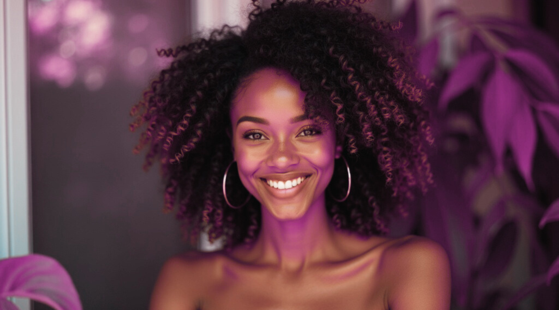 A smiling Black model with a tight coil hairstyle