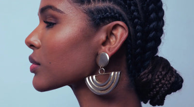 A profile portrait of a stunningly beautiful Black woman with braids tied in a low bun