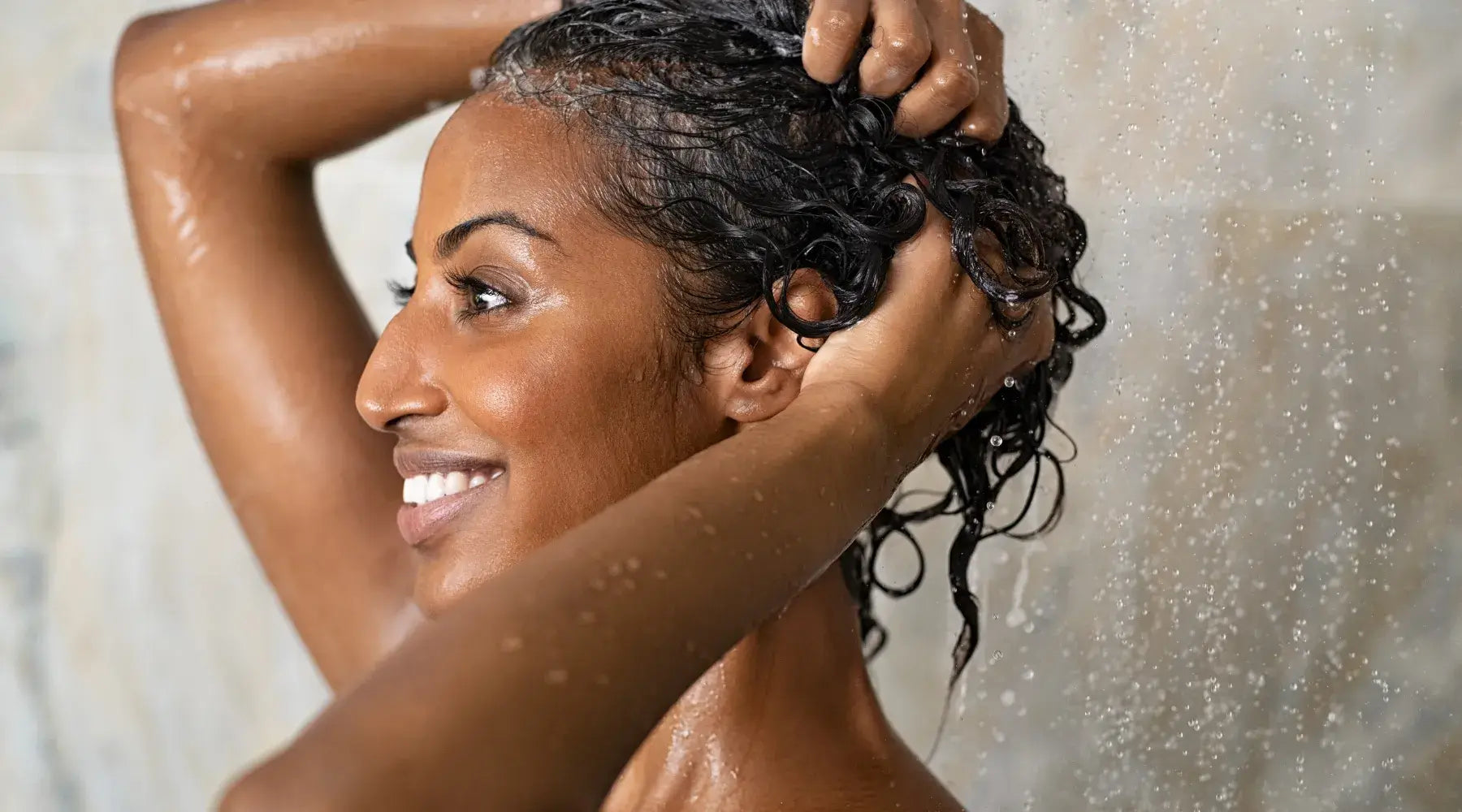 A Black woman washes her natural hair in the shower