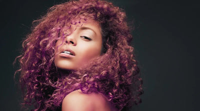 A beautiful Black woman with long deep wave hair looks over her shoulder